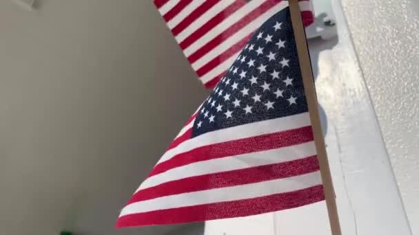 Pequeñas banderas americanas como señal de patriotismo en EE.UU. colgando de la casa y soplando fuera del día de verano. De cerca. — Vídeo de stock