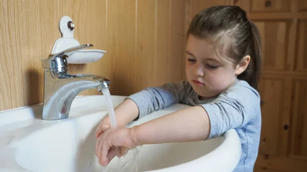 Sad girl washing hands under the water. Tries to protect herself from contagious diseases during quarantine. — Stock Photo, Image