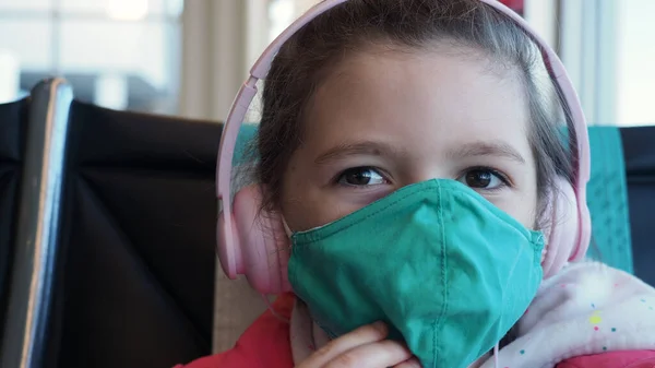 Kapatın. Yeşil maskeyi çıkarmaya çalışan kahverengi gözlü ve pembe kulaklıklı kız kameraya bakar. Yeni gerçeklik kavramı