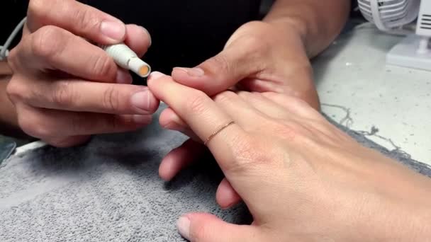 Primer plano de imágenes de hombre artista de manicura en camiseta negra haciendo las mujeres esmalte de uñas con herramienta de taladro de lima de uñas eléctrica. Concepto de belleza y salud. — Vídeos de Stock