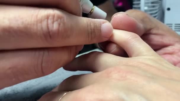 Zoom. Schönheits- und Gesundheitskonzept. Mann Maniküre Künstler in schwarzem T-Shirt macht Frauen Nagellack mit elektrischer Nagelfeile Bohrwerkzeug. — Stockvideo