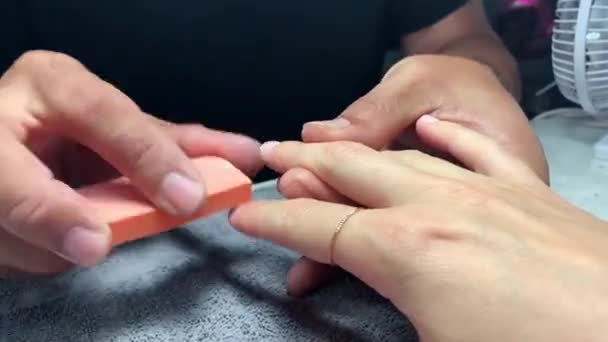Närbild. Man manikyr artist i svart t-shirt med hjälp av en nagelfil gör kvinnor nagellack, Korrigering av kvinnliga naglar. Skönhet och hälsovård. — Stockvideo