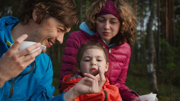 Kapatın. Mutlu genç aile, bahar kampı tatilinde kahvaltıda babalarının elindeki küçük böceklere hayran olur ve onları tedavi eder. Aile İlişkisi Etkinliği.