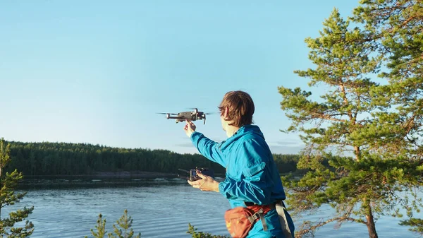 Young hiker holding a mini drone with camera ready to be released in the sky over sunset. Traveler uses innovation aviation unmanned aircraft quad copter for taking aerial photo and video from above
