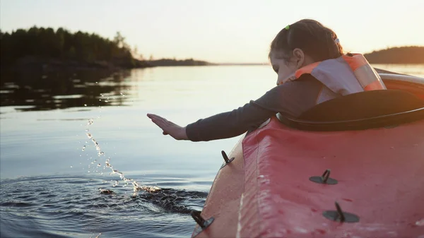 Düşünceli 5 yaşındaki çocuk suyla oynuyor ve düşen damlaların suya düşüşünü seyrediyor. Karanlık ormanlara karşı sakin bir göl boyunca uzanan küçük kırmızı kanoda oturuyor.