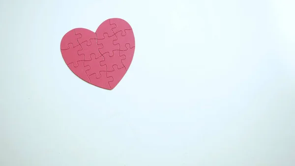 Kopyala lütfen. Beyaz masa arkasında küçük kırmızı kalp şeklinde yapboz. Üst görünüm