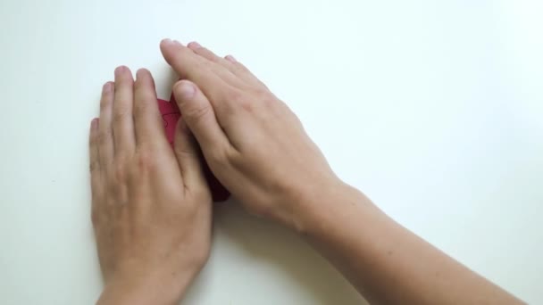 Ovanifrån av kvinnor händer öppna dolda små röda hjärta formade pussel från pappersblock pussel på vitt bord bakgrund — Stockvideo