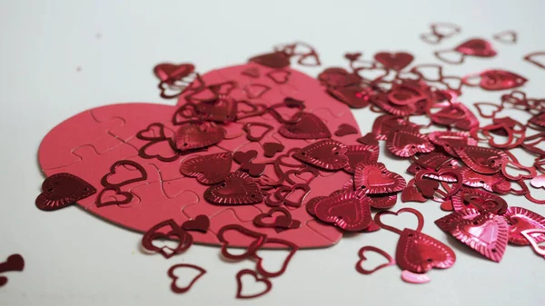 Beyaz masa arka planında kırmızı yapboz şeklinde bir sürü parlak kalp var. Sevgililer Günü 'nü kutlayalım.