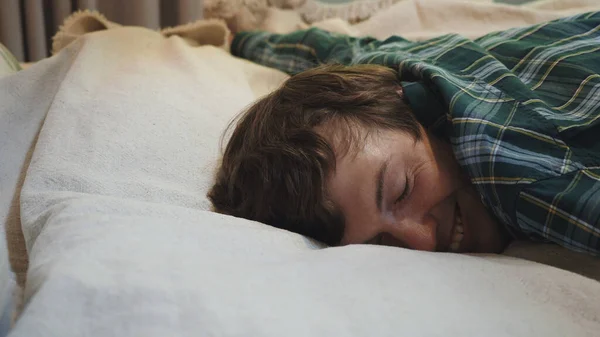 Wyczerpany młodzieniec zasypiający na łóżku, nie odczuwający energii po ciężkim dniu pracy. Biznesmen upada na łóżko, potrzebuje odpoczynku w domu. — Zdjęcie stockowe