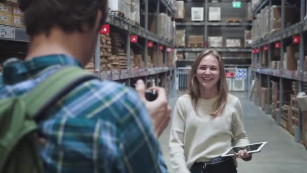 사진가인 남자는 거대 한 도매점의 선반 사이에 아름다운 금발의 젊은 여자와 만족하고 있다. 닫아 — 비디오