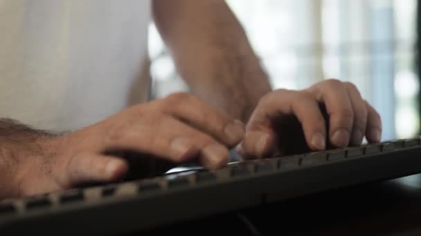 Brazos peludos de hombre en camiseta blanca escribiendo rápidamente en el teclado negro de la computadora en la biblioteca, estantes de fondo. El empresario masculino está en la librería o en la oficina. De cerca. — Vídeo de stock