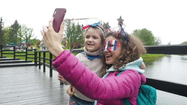 Jolie fille et femme portent des symboles Etats-Unis drapeau national, heureusement parler en vidéoconférence par smartphone ensemble, célébrer le 4 Juillet dans le parc. Activité technologie style de vie téléphone portable utilisation concept — Photo