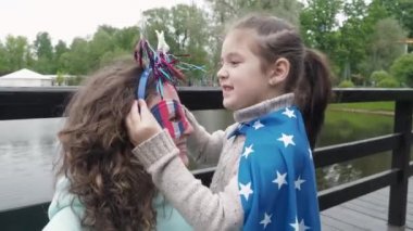 Komik maskeli ve pelerinli mutlu vatansever anne ve kız Amerikan bayramında lunaparkta aptalca boynuzlar giyerler. Bağımsızlık Günü Kutlama Konsepti