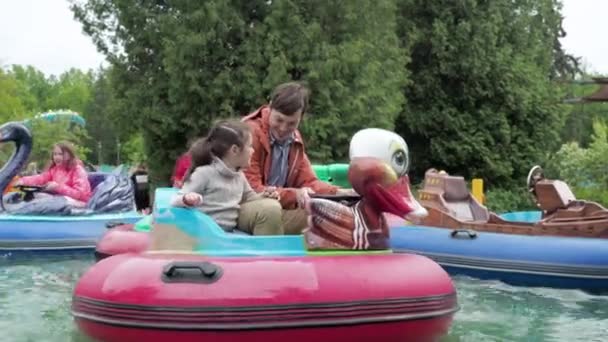 Divo Ostrov, Saint-Petersburg, Russia - May, 2021: Happy family father and daughter having fun sit in inflatable seats and sail on water in funfair in amusement park. Качественное время с понятием семьи — стоковое видео