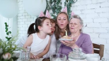 Kutlama ve aile kavramı. Dört kadın jenerasyonu 85. yaş gününü kutluyor, büyükannem pasta tutuyor ve birlikte mum üflüyor. Kadın ailesi, saygı ve sıcak ilişkiden zevk alır.