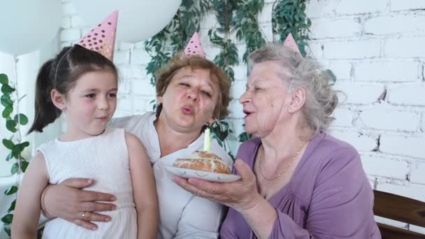 Tre generazioni di donne festeggiano 85esimo compleanno della donna anziana, nonna tiene torta e felice soffiando candela tutti insieme. Famiglia femminile godere, rispetto e relazione calorosa. Concetto di celebrazione — Video Stock