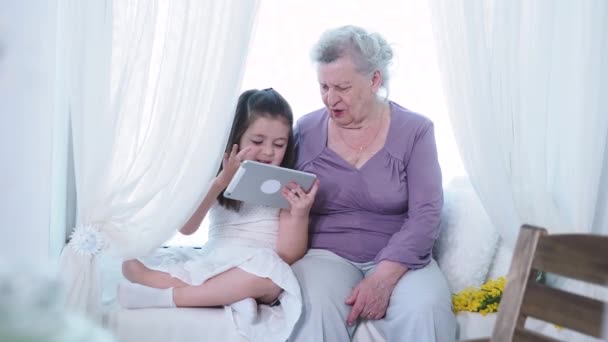 Nettes kleines Vorschulmädchen, das alte reife Oma-Kindermädchen mit einem digitalen Tablet unterrichtet. Großeltern und Enkelkinder der zweiten Generation erforschen neue Technologien — Stockvideo