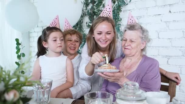 Celebração e conceito de família. Rapariga acende uma vela no bolo de aniversário celebrando o velho aniversário da avó 85 todos juntos quatro geração de mulheres. Família feminina desfrutar, respeito e relação calorosa — Vídeo de Stock