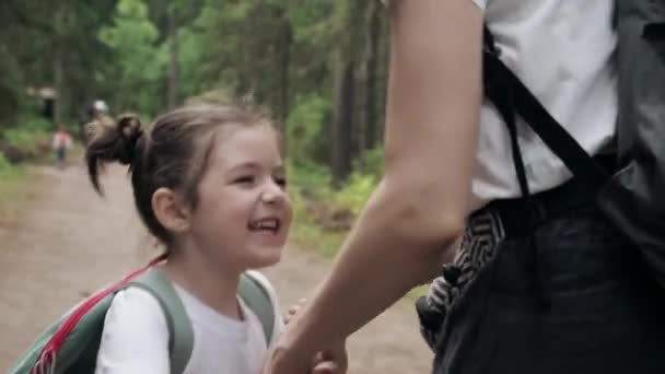 Feliz sonrisa linda hija saltando alrededor de su joven madre en el parque forestal tomados de la mano. Felicidad estar juntos, sueño del niño, libertad o vacaciones familiares juntos concepto. Movimiento lento — Vídeos de Stock