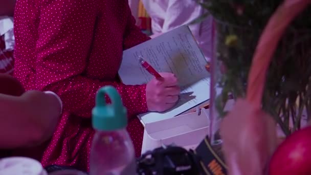 ノートにペンでメモを取る赤いドレスの女性 — ストック動画