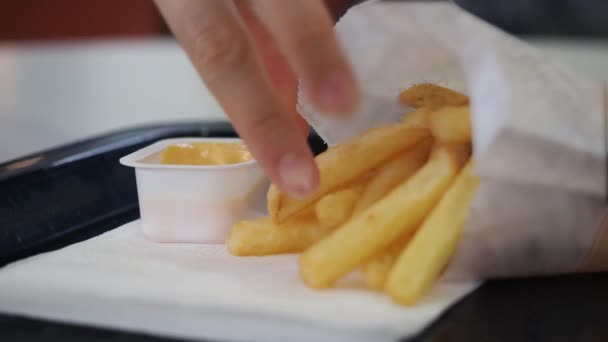 Vrouwen dompelen frietjes met de hand in mosterdsaus. Sluiten. — Stockvideo