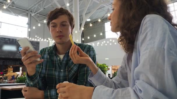 Attractive woman feeds her husband french fries in a cafe — Stock Video