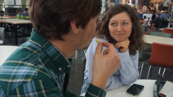 Ελκυστική γυναίκα θαυμάζοντας τον άντρα της τρώγοντας τηγανιτές πατάτες σε ένα καφέ — Αρχείο Βίντεο