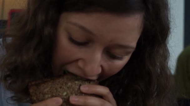 小さなレストランでサンドイッチを食べる魅力的な空腹の女性。閉じろ! — ストック動画