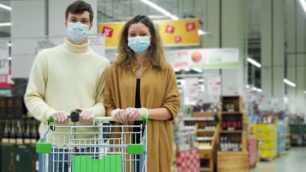 Paar draagt masker en handschoenen van virus stands met kar in de winkel Time lapse — Stockvideo