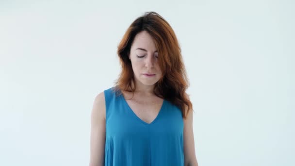 Porträtt av bedårande unga röda hår flicka i blå klänning öppnar ögonen och tittar på kameran stående isolerad över vit vägg bakgrund i studion. Skönhetsbegreppet — Stockvideo