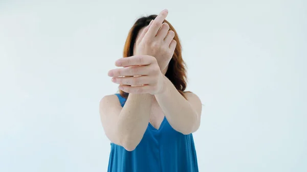 Mavi elbiseli sevimli kızıl saçlı kadının portresi yüzünü kapatır ve elleri stüdyodaki beyaz duvarın arkasında tek başına durur. Güzellik konsepti