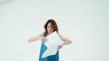 Güzel kızıl saçlı kadın elinde kağıtları tutuyor ve atıyor. Beyaz arka plan. Dertsiz, mutlu bir kadın belgelerle eğleniyor. Yeni dönem, özgürlük stresi çalışma kavramı