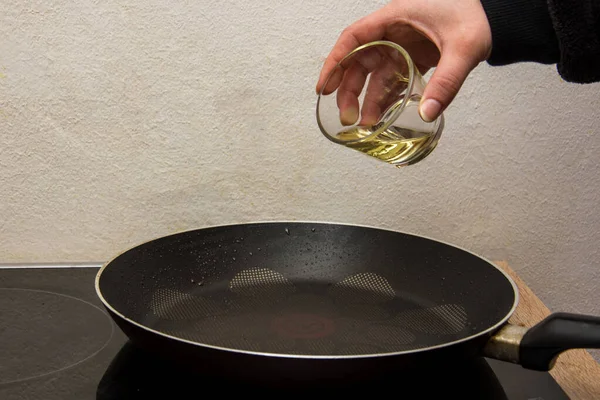用玻璃杯把生物油放进热的黑锅里 免版税图库图片
