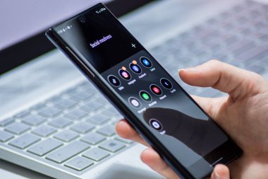Viyana / Avusturya / 14 Kasım 2020: Siyah akıllı telefonu elinde tutan genç kadın gri defter üzerinde