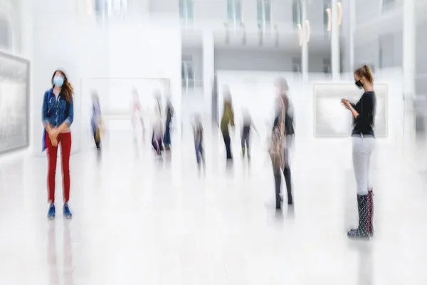 abstract image of people in the lobby of a modern art center with a blurred background