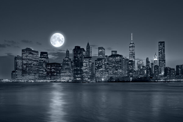 Panoramic view New York City Manhattan downtown skyline at night with skyscrapers blue tonality and bright full moon