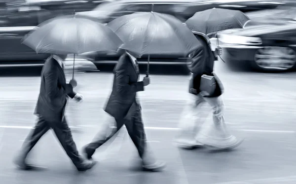 Mensen uit het bedrijfsleven lopen in de straat op een regenachtige dag beweging vervagen — Stockfoto