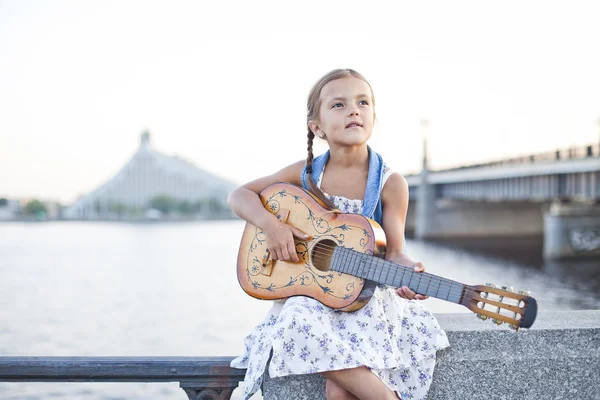 Girl playing guitar on river embankment — Stock Photo, Image