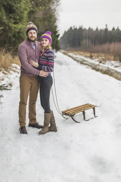 Jovem casal ter um trenó caminhada floresta de inverno — Fotografia de Stock