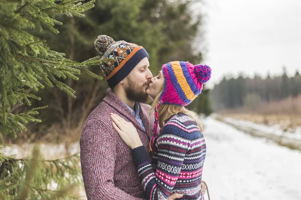 Jovens pessoas estão se beijando na floresta de inverno — Fotografia de Stock