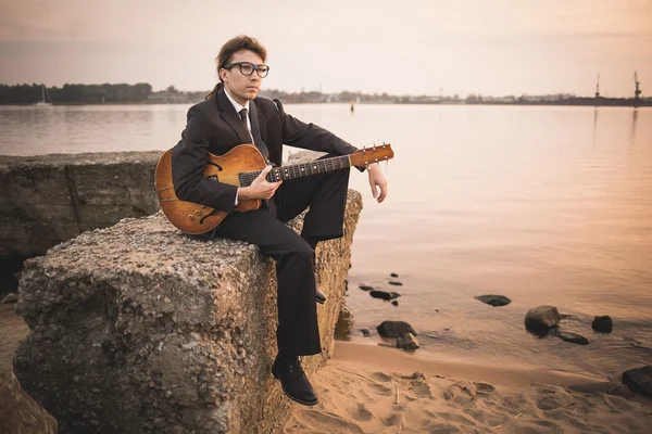 Músico masculino y su guitarra en la orilla — Foto de Stock
