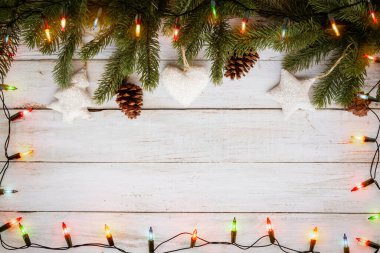 Noel ışıkları ampulü ve çam yaprakları beyaz tahta üzerinde, çerçeve sınır tasarımı. Mutlu Noeller ve yeni yıl tatili geçmişi. en üstteki görünüm.