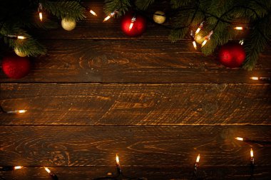 Noel arkaplanı - Noel ışıkları ampulü ve çam yaprakları ahşap döşeme, çerçeve sınır tasarımı. Mutlu Noeller ve yeni yıl tatili geçmişi. en üstteki görünüm.