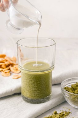 Matcha with milk on a gray background next to fruit chips. Breakfast concept