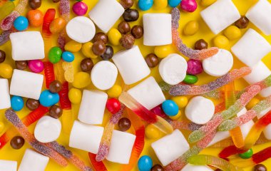 Sarı arka plandaki farklı tatlıların arkaplan dokusu. Yukarıdan görüntüle