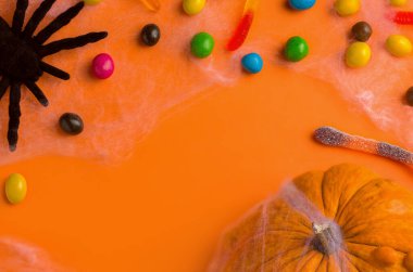 Cadılar Bayramı geçmişi. Turuncu bir arka planda, balkabağı ve tatlı. Boşluğu kopyala