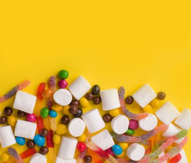 Bir sürü tatlı reçel, marmelat, fıstık, çikolata. Sarı arka planda. Boşluğu kopyala