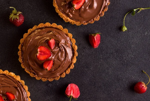 Dessert tart chocolate with strawberries on a black background. View from above. Copy space