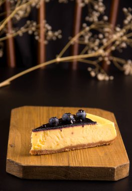 The concept of cakes. Cheesecake with blueberries and caramel on a black background
