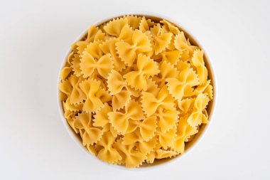 Çiğ pişmemiş Farfalle makarna makarna makarna beyaz kâse ahşap arka plan fesleğen domates pesto sosu ev yapımı İtalyan yemeği organik buğday vegan spagetti sağlıklı bir yemek için